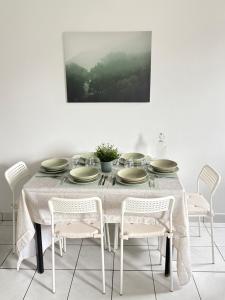 einem Esstisch mit weißen Stühlen und einem Gemälde in der Unterkunft F3 confortable à 2 min du métro et ambiance cinéma in Saint-Ouen