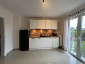 a kitchen with white cabinets and a black refrigerator at Moderne Erdgeschosswohnung und eigenem Garten für bis zu 4 Personen in Ketsch +2 photos