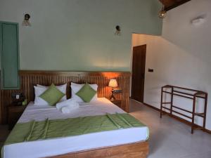 a bedroom with a large bed with green and white pillows at River Shades Hotel in Hikkaduwa +40 photos