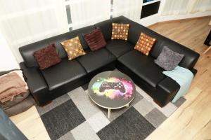 a black leather couch with pillows and a table at La suite Gaming - Suite 8 personnes in Rethel