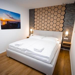 a white bed in a bedroom with a painting on the wall at KAR-LA apartments in Dolní Věstonice +74 photos