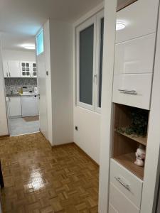 cocina con armarios blancos y suelo de madera en Johanna Apartmani, en Belgrado 3 fotos más