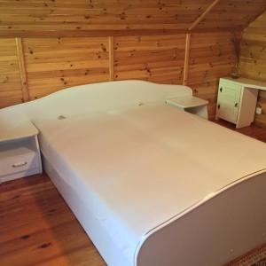 a large white bed in a room with wooden walls at Domek Letniskowy in Stare Jabłonki +3 photos