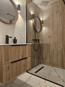 a bathroom with a shower with a sink and a mirror at V-House in Vama Buzăului