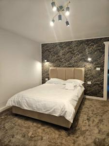 a bedroom with a large bed with a stone wall at V-House in Vama Buzăului