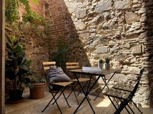a patio with a table and chairs and a stone wall at Stone Rustic Beach apartment in Blanes