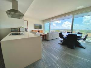 Una cocina y una sala de estar con mesa y sillas. en Rooftop pool- family apartment- ocean view -close, en Cancún