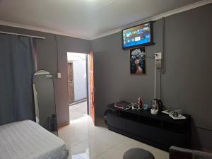 - une chambre avec un lit et une télévision murale dans l'établissement THE 643 Guesthouse, à Roodepoort