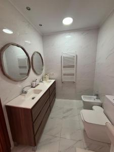 ein Badezimmer mit Waschbecken, Toilette und Spiegel in der Unterkunft Casa con PISCINA y CINE in Paterna