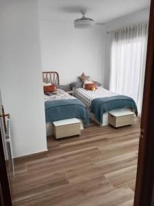 zwei Betten in einem weißen Zimmer mit Holzboden in der Unterkunft Casa con PISCINA y CINE in Paterna