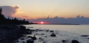 a sunset over a body of water with rocks at Уютная квартира в 10 минутах от моря in Aseri