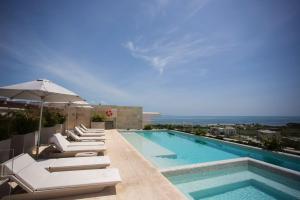 カンクンにあるLuxury 3BR Condo* rooftop pool, near the beachのラウンジチェアとパラソル付きのスイミングプールを併設しています。