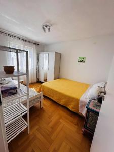 a bedroom with a yellow bed and a wooden floor at Apartment Second Home in Tribunj