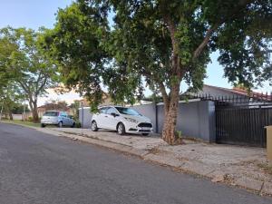 une voiture blanche garée à côté d'un bâtiment à côté d'un arbre dans l'établissement THE 643 Guesthouse, à Roodepoort