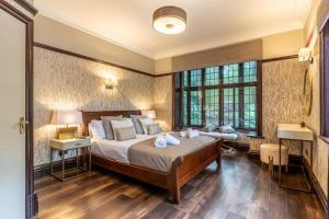 a bedroom with a large bed and two windows at The Tudor Mansion in Bournemouth
