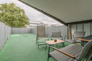 a patio with chairs and a table and a tree at Exklusive große Ferienwohnung für 7 Personen, Parkplatz, Balkon, 3 Schlafzimmer in Bayreuth
