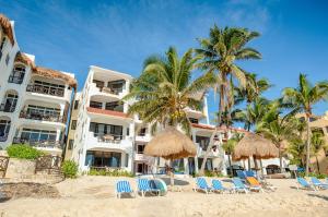 a hotel on the beach with chairs and palm trees at Luna Azul 8: Beachfront Paradise in Akumal in Akumal