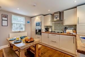 une cuisine avec des armoires blanches et une table en bois dans l'établissement Stamps Cottage - Uplyme, à Uplyme