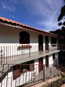 a white house with a balcony with flowers on it at Villaggio Harmonia Monte Verde in Camanducaia