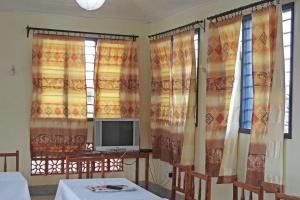 Habitación con cortinas, TV y mesa. en Voi Lutheran Guesthouse, en Voi