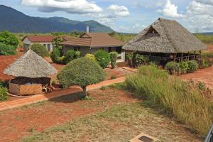 a house with two thatch huts in a field at Voi Lutheran Guesthouse in Voi