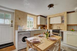 a kitchen with a table and a washer at Holly Cottage in Swanage