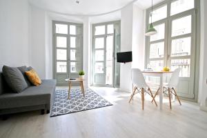 uma sala de estar com um sofá e uma mesa em MalagaUrbanRooms - Central Suites em Málaga