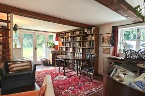ein Wohnzimmer mit einer Bibliothek mit einem Tisch und Stühlen in der Unterkunft Far End Cottage in Fyfield