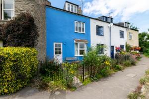 a blue and white house with a fence at Meadow Cottage in Bridport