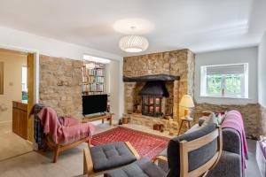 - un salon avec un mur en pierre et une cheminée dans l'établissement Rose Cottage - Stoke Abbott, à Stoke Abbott