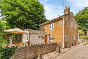une vieille maison en briques avec un parapluie devant dans l'établissement Rose Cottage - Stoke Abbott, à Stoke Abbott
