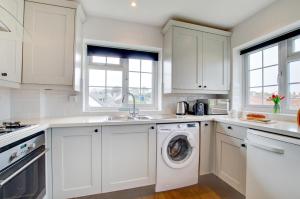 a kitchen with white cabinets and a washing machine at Sands in Swanage