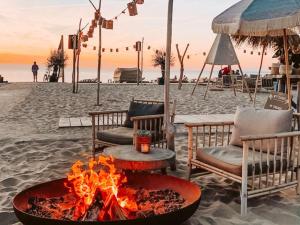 a fire pit on a beach with chairs and a table at Costa C en E in Noordwijk
