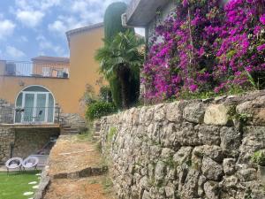 eine Steinmauer mit lila Blumen vor einem Haus in der Unterkunft Sensivilla Guest House - Grasse - Costa Azzurra in Grasse