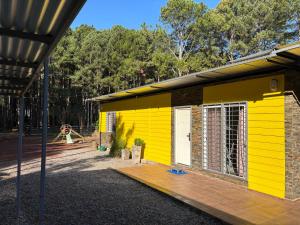 una casa gialla con un parco giochi sullo sfondo di Un lugar ideal para disfrutar la naturaleza a Colonia Estrella