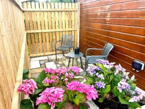a patio with two chairs and pink flowers at Little Rock Cabin in Ballynagore