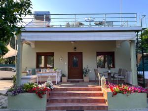 a house with a staircase leading to a porch with flowers at Pelion Malaki- Casa Verde in Malaki