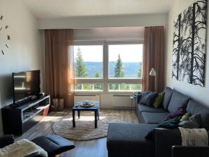 a living room with a couch and a large window at Näköalahuoneisto 426 in Syöte