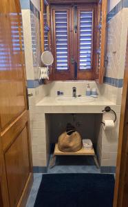 a bathroom with a sink and a basket on a shelf at Schicciolina in Stromboli