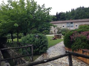 a garden with a fence and flowers and a building at Lady Frantoio Toscano in Corsanico-Bargecchia