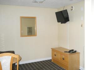 Habitación con tocador y TV en la pared. en TC Motel, en Medicine Hat
