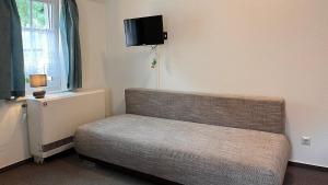 a room with a couch and a tv on the wall at Hostel Ziegenrück in Ziegenrück