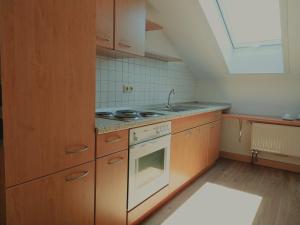 a kitchen with wooden cabinets and a stove top oven at Dorfschänke DEGGENDORF Hotel & Apartmenthaus in Deggendorf +35 photos
