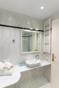 a white bathroom with a sink and a mirror at Athens Plaka Acropolis Suites in Athens +45 photos