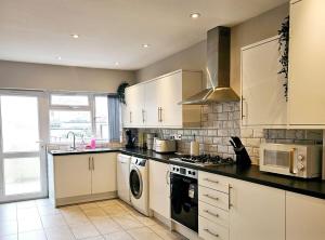 a kitchen with white cabinets and a stove top oven at Saxe House in Sheldon