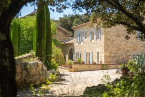 an exterior view of a stone house with trees at Mas Bella Cortis in La Garde-Adhémar