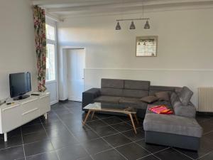 a living room with a couch and a tv at Le Chai de Montaigne in Montcaret