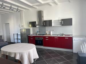 a kitchen with red cabinets and a table in it at Le Chai de Montaigne in Montcaret
