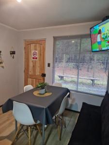 a dining room with a table and chairs and a tv at Cabaña arenal in Pucón