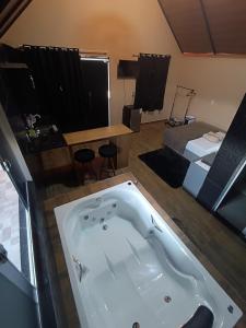 a bath tub in a room with a bed at Chalé Montanhez hidromassagem piscina in Caparaó Velho +26 photos